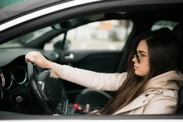 Photo of Side view of a beautiful young Caucasian woman driving a car