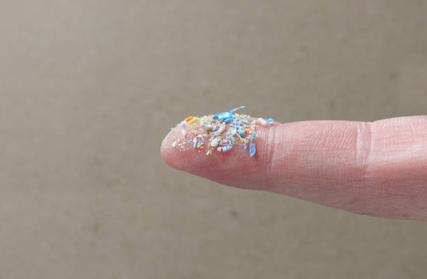 A bunch of plastic rubbish that cannot be recycled. Close up side shot of microplastics on human finger. Creative concept of water pollution and global warming. Climate change idea. microplastic photos stock pictures, royalty-free photos & images
