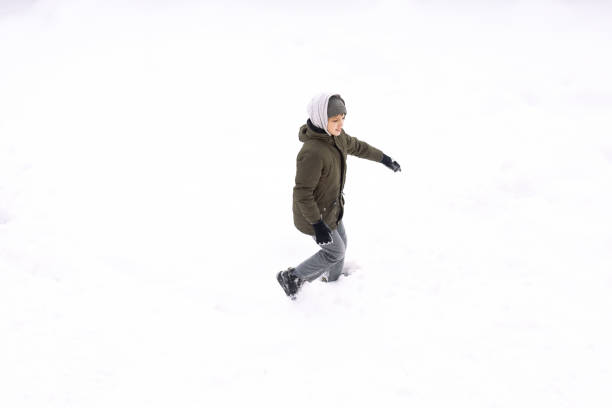 istock Conceptual image of boy runnin lying down on the ground covered with snow isolated on white, top view from drone 1298178044