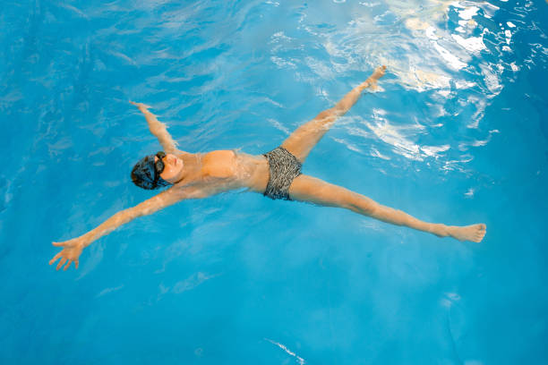 istock Boy swimming in indoor pool having fun during swim class 1298179945
