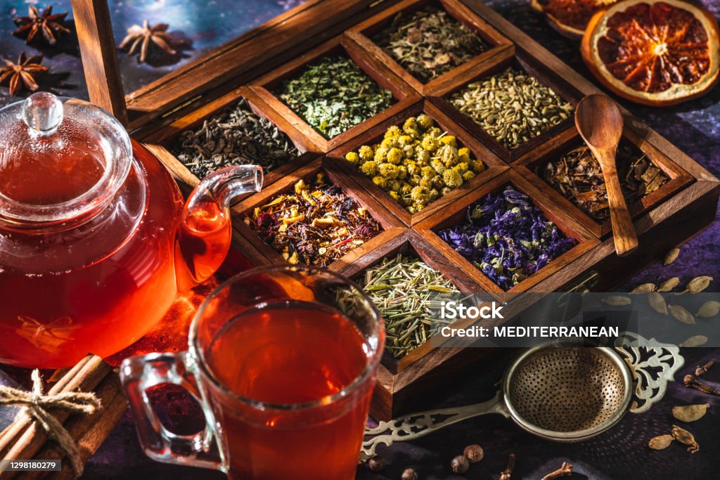 Red tea with a box of tea herbs and aromatic spices Red tea with a box of tea herbs and aromatic spices with glass teapot and teacup Dried Tea Leaves Stock Photo