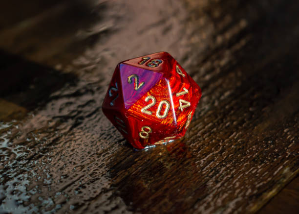 Marbled red 20 sided dice on a wet wooden surface stock photo