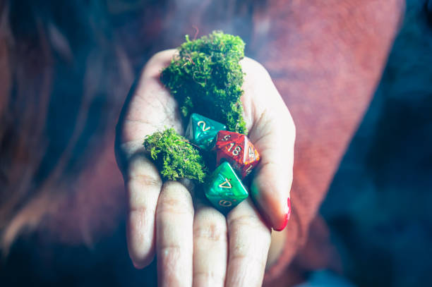 rpg dice in a hand A red 20 sided die, two eight sided dice and moss in a woman's hand in a dark and smoky environment developing 8 stock pictures, royalty-free photos & images