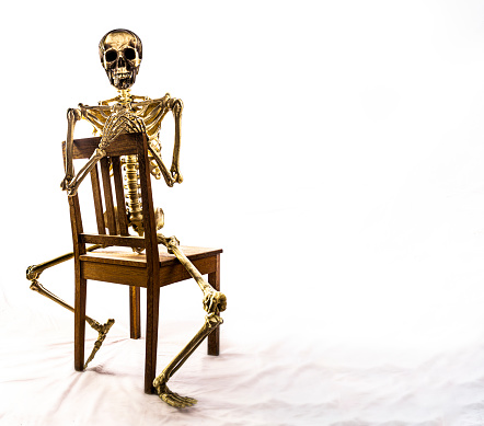 Skeleton on a chair in a studio, high key processed
