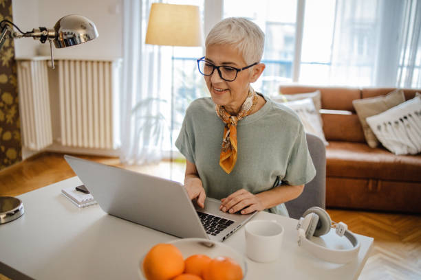 istock Senior woman is using laptop at home 1298186688