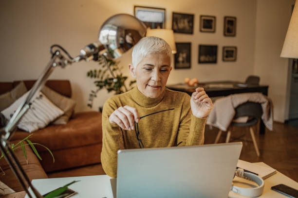 istock Mature woman is using laptop and working from home 1298186695