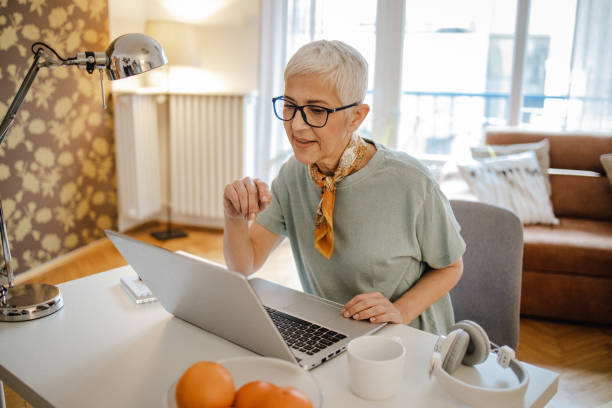 istock Senior woman is using laptop at home 1298186733