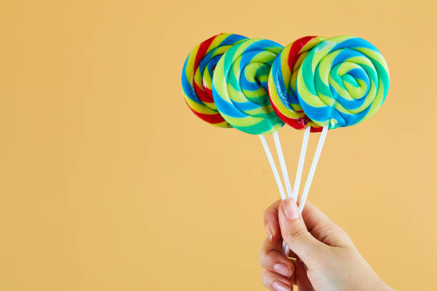istock Hand holding colorful lollipops on orange background 1298188016