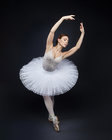 attractive ballerina poses gracefully in the studio on a black background