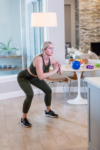 istock Woman exercising at home doing squats 1298192357