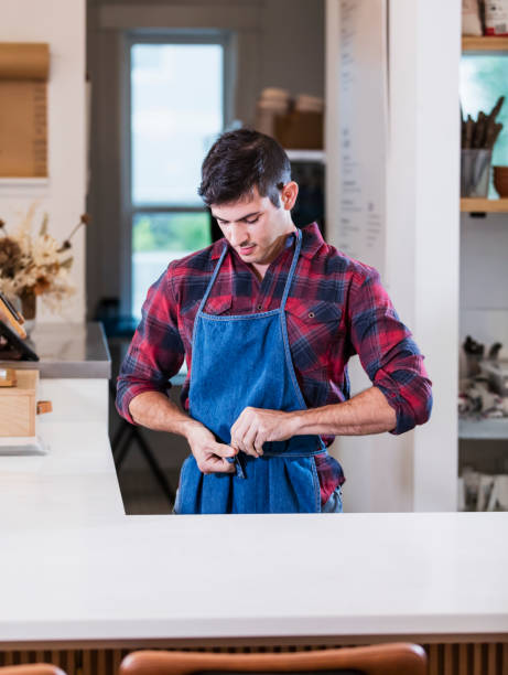 istock Hispanic man working in cafe, putting on an apron 1298193190