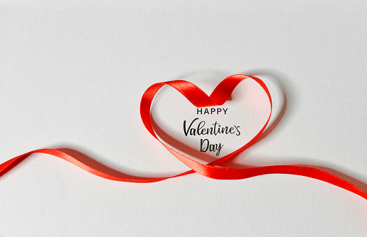 Red ribbon in heart shape - Happy Valentine's Day on white background.
 Horizontal composition with copy space. Love and Valentine's Day concept.