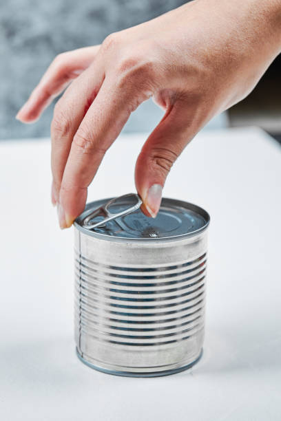 istock Hand holding a tin with boiled green peas on a white table 1298197228