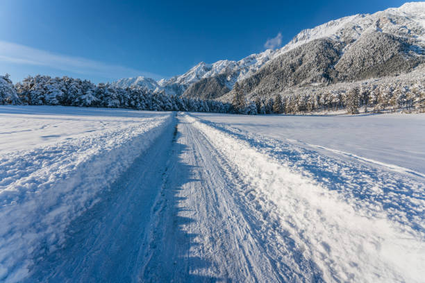 Deep snow covered walking path through sunny alpine winter landscape in Wildermieming, Tirol, Austria
