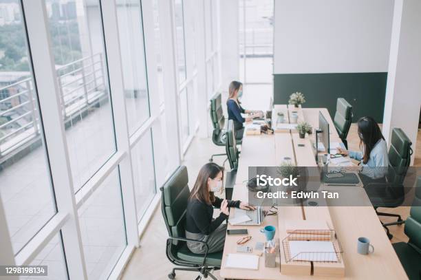Asian Chinese Beautiful Women With Protective Facemask Working In Open Plan Office Observing With New Sop And Social Distancing Illness Prevention Safety Precautions Stock Photo - Download Image Now