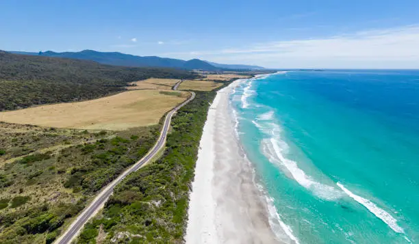 Stunning high angle aerial panoramic drone view of Denison Beach and the A3 Tasman Highway just north of the village of Bicheno on the east coast of Tasmania, Australia on a sunny day.