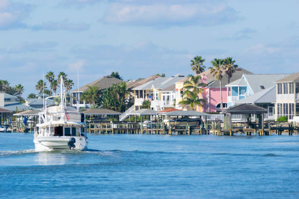 Waterfront Homes and Yacht in Florida Colorful homes on intracoastal waterway near St. Augustine, Florida with yacht in foreground and palm trees. daytona beach stock pictures, royalty-free photos & images