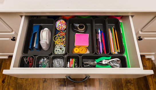 Organized desk drawer with office supplies in bins