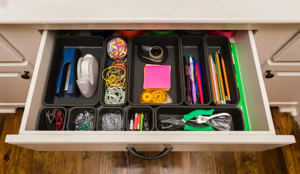 Photo of Organized desk drawer with office supplies in bins