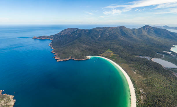 オーストラリアのタスマニアにある有名なワイングラス湾を持つフレシネ半島と国立公園の高角パノラマ空中ドローン映像。背景にはグラハム山(左)とフレイシネ山(右)。 - freycinet national park ストックフォトと画像