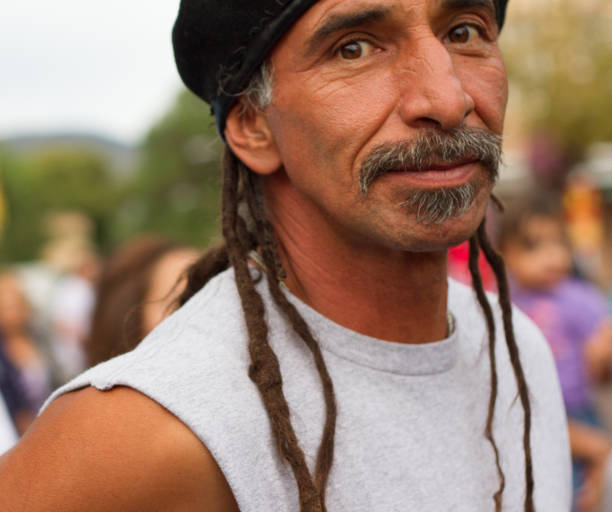 Santa Fe, NM: A Latino man with locs and facial hair on the Santa Fe Plaza looks at the camera. Close-up shot.