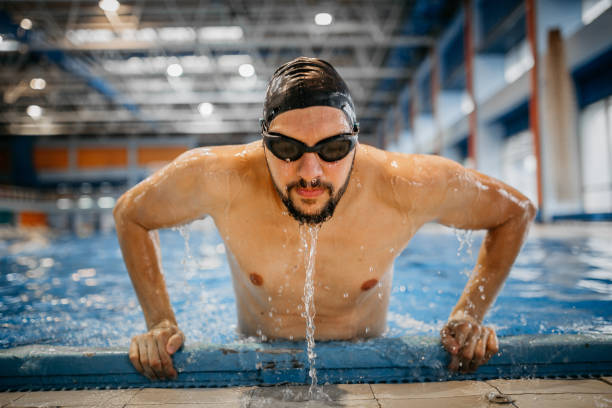Freestyle stroke swimming competition start for men at a swimming tournament. Referees at the side of a swimming pool.