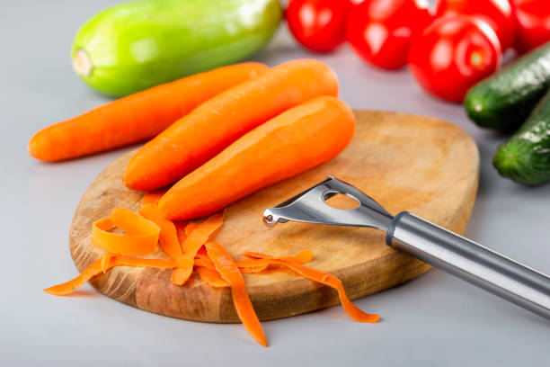 istock Preparing vegetables.  Peeling carrots on wooden kitchen table with vegetables. 1298205108