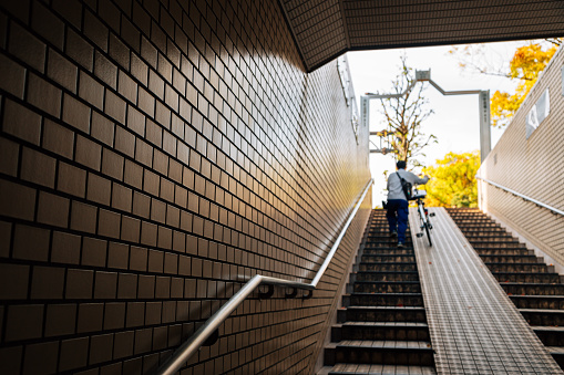Man climbing stairs with bicycle in Japan