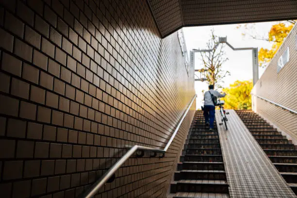 Photo of Man climbing stairs with bicycle in Japan