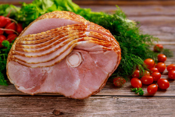 istock Spiral sliced hickory smoked ham with fresh herb and tomatoes. 1298223056