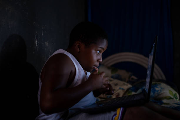 istock African boy working on his computer in the dark on his bed 1298225678