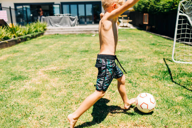 istock Boy kicking football in backyard 1298227954