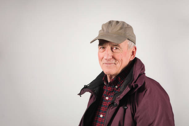 senior mann heiter porträt in warmen winterkleidung und trägt eine baseballkappe - baseball cap old red caucasian stock-fotos und bilder