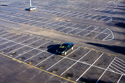 January 23, 2020 - Nashville, Tennessee, U.S.: Two cars sit all alone in a large empty parking lot at Nissan Stadium. A tourist rides a scooter in the background.