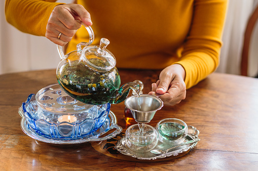 Woman pouring tea from glass pot into cup, Tea ceremony concept