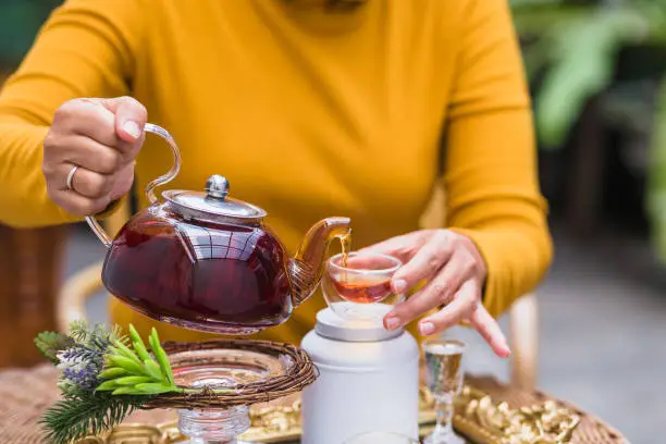 Woman pouring tea from glass pot into cup, Tea ceremony concept