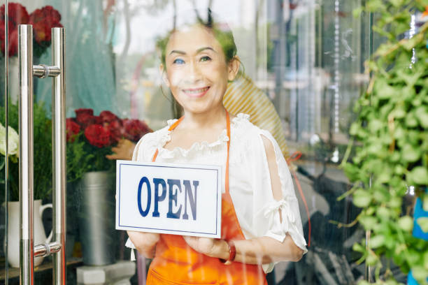 istock Flower shop owner turning open sign 1298236584