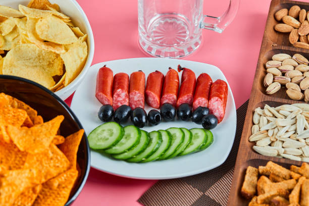 istock Assorted snacks and plate of sausages on the pink table 1298237426