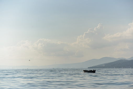 wooden boat with no people in bay sea with sky and mountain background, horizontal stock photo image backdrop
