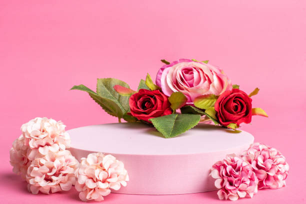 istock Empty pink platform for product display with pink flowers and pink background 1298240741