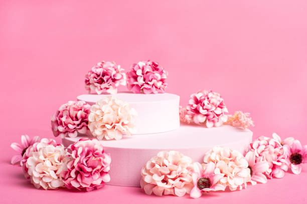 istock Empty pink platform for product display with pink flowers and pink background 1298240742