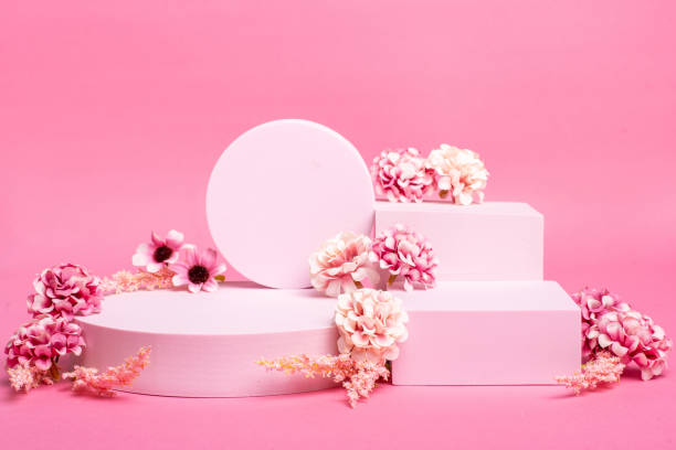 istock Empty pink platform for product display with pink flowers and pink background 1298240743
