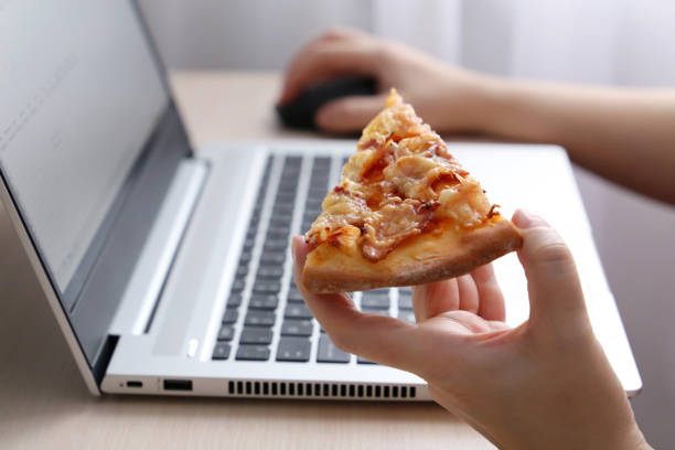 istock Woman eating pizza during work at laptop 1298241557