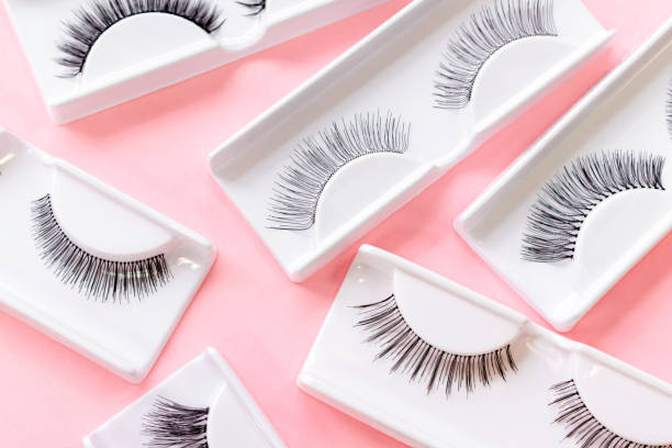 istock Different fake eyelashes on trendy pastel pink background. Beauty pattern. Makeup accessories. Cosmetics products for women. Bright beautiful backdrop. Closeup. 1298242116