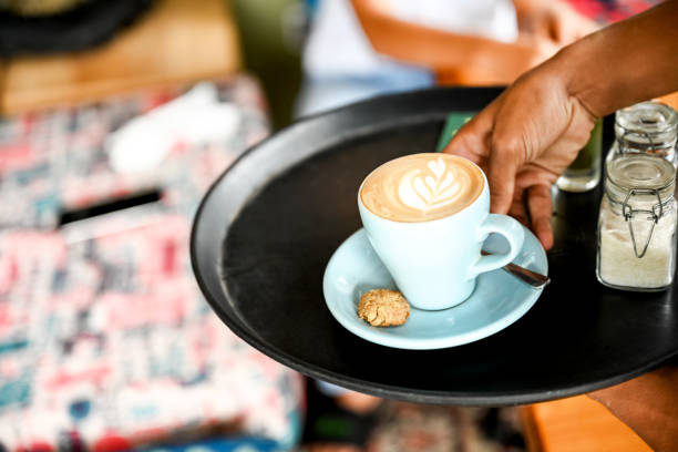 ウェイターはカプチーノを提供しています - latté coffee tray froth ストックフォトと画像
