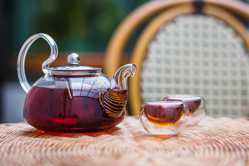 A glass teapot and tea cups on rattan table at home, Tea ceremony concept