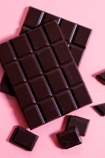 istock Dark chocolate bars on pink background, top view. 1298244930