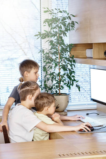 istock Young boy pupils sit on wooden chair at desk with computer 1298245021
