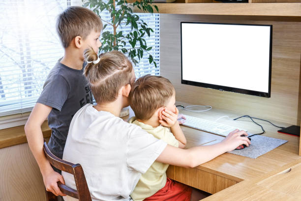 istock Young boy pupils sit on wooden chair at desk with computer 1298245159