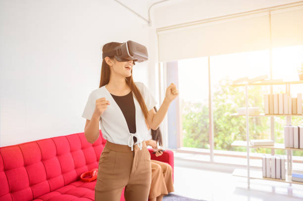 istock Asian woman using VR headset at home. Wearing virtual reality headset for playing online game. 1298249072